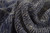 Dense hand-knotted wool texture in heathered navy, denim and beige yarns across the surface