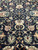 Dark field detail showing the symmetrical floral vine lattice in cream, green and gold wool