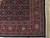 Corner detail showing red main border, blue rosettes, ivory fringe and tight hand-knotted weave