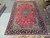 9'8" x 15'6" Persian Isfahan rug displayed flat on showroom floor beside rolled Oriental rugs