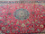 Close-up of cherry red field with blue palmettes, green leaves and ivory vine scrollwork