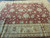 12x15 Indian Agra rug detail showing green and ivory palmettes across the rust wool field