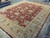 Corner angle of hand-knotted wool Oriental rug in rust and gold with white cotton fringe