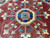 Central octagonal medallion in navy and ivory with radiating hooked arms on deep red ground