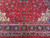 Close-up of navy border, teal guard bands and ivory arabesques framing the red field