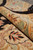 Rolled edge revealing dense hand-knotted pile, soft green border and coral floral detail