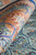 6 x 9 turquoise silk rug rolled to show peach, gold and red border bands
