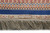 Close view of blue band, ivory cartouche panel and thick silk fringe along the rug end