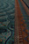 Side border of the silk rug in rust and gold beside the deep teal field