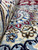Close-up of wool and silk pile showing cream border flowers in brown, blue and red