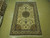 Hand-knotted 7x10 Tabriz rug displayed flat on showroom floor showing ivory field and green border