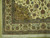 Corner detail showing camel gold spandrel, perched birds, layered green border and ivory cotton fringe