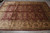 Burgundy and ivory hand-knotted Indian rug photographed on grey floor showing full all-over floral layout