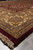 Corner perspective of gold ivory border, palmette rosette and deep burgundy selvage above pale fringe