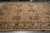 Hand-knotted wool rug on warehouse floor showing camel beige field and repeating brown star medallions