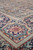 Angled view of ivory and navy border medallion showing hand-knotted wool pile and crimson floral detail