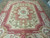 Angled full view of the 8'10 x 11'9 needlepoint rug on tiled floor