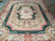 Formal 9' x 12' needlepoint rug photographed from the opposite end on a tiled showroom floor