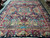 Living room sized Persian rug laid on tile showing full pictorial layout and indigo border