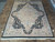 Tabriz design medallion rug photographed on stone floor showing full black border and ivory field