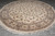 Round wool and silk rug displayed on grey tile floor showing cream field and ivory fringe