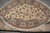 Overhead angle of the round rug showing scrolling vines, palmettes and wide taupe main border