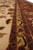 Border detail showing gold running vine guard stripe beside deep rust main border