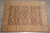 Brown and peach hand-knotted Zigler rug photographed flat on grey tile showroom flooring