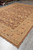 Perspective shot of hand-knotted wool rug corner, warm brown field meeting golden guard borders