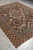 Hand-knotted Pakistani wool rug seen lengthwise, saffron and red outer border framing the panel field