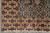 Corner of the rug with ivory fringe, red lattice border and black arabesque guard stripe