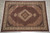 Ivory floral border frames the dark herati field on this hand-knotted 10x13 wool and silk rug