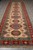 Pakistani Kazak wide runner rug 5x19 displayed lengthwise on grey tile showroom flooring