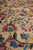 Wool pile texture close-up with magenta blossoms, sky blue florets and olive green stems