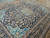 Angled view of navy Kashan rug revealing dense wool pile, sky blue guard borders and corner spandrels
