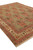 Beige and rust wool rug viewed from the corner with cotton fringe and floral border
