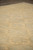 Angled floor view showing soft green field and beige medallions receding across the hand-knotted wool pile