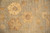 Close-up of an ivory rosette and gold vine scroll on the light sage field