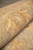 Rug rolled to display its supple handle and gold serrated leaf drawing along the border