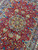 Close-up of the burgundy field showing blue vases, columns and a golden 8 point rosette medallion