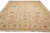 Sage beige floral rug photographed at an angle showing gold palmettes and ivory fringe ends