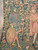 Bearded figure in blue patterned robe holding oval shield with rampant beast beside Gothic banderole