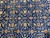 Detail of cream palmettes, light blue leaves and brown rosettes knotted on a midnight navy field