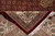 Folded corner revealing tight knotting on the reverse beside ruby herati field and cotton fringe