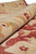 Close rolled edge showing thick natural wool pile in cream, apricot and deep red tones