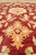 Field close-up of golden palmette and cream rosette blossoms on antique red wool ground