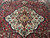 Ivory medallion with black core and coral rosettes anchoring the center of this tribal rug