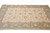 Beige and green 8x11 area rug photographed from the end, all over vine and palmette design