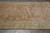 Overhead close view of the rust field meeting the pale green floral border on wool pile