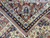 Folded corner showing plush fine wool pile, ivory palmette border and navy guard stripe